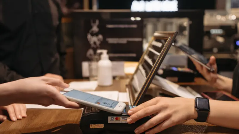 Una persona tocando el teléfono en una terminal de pago