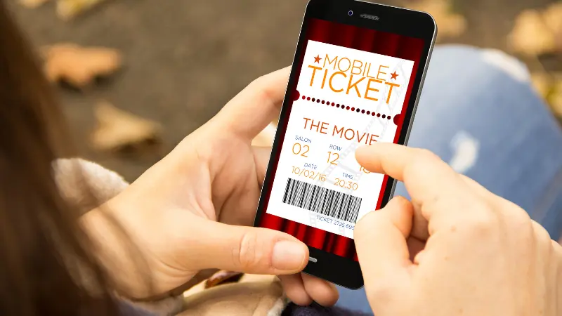 A woman reservation cinema e-ticket with a smartphone in the park