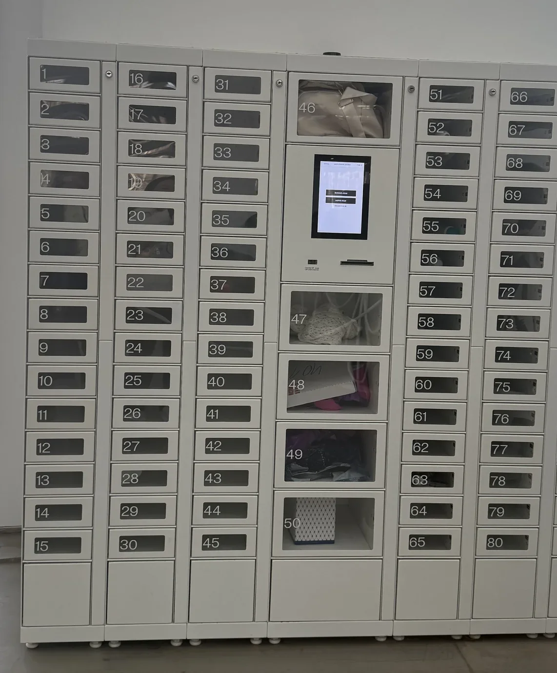 Custom-built SwiftForce smart locker wall with central touchscreen and glass-front compartments